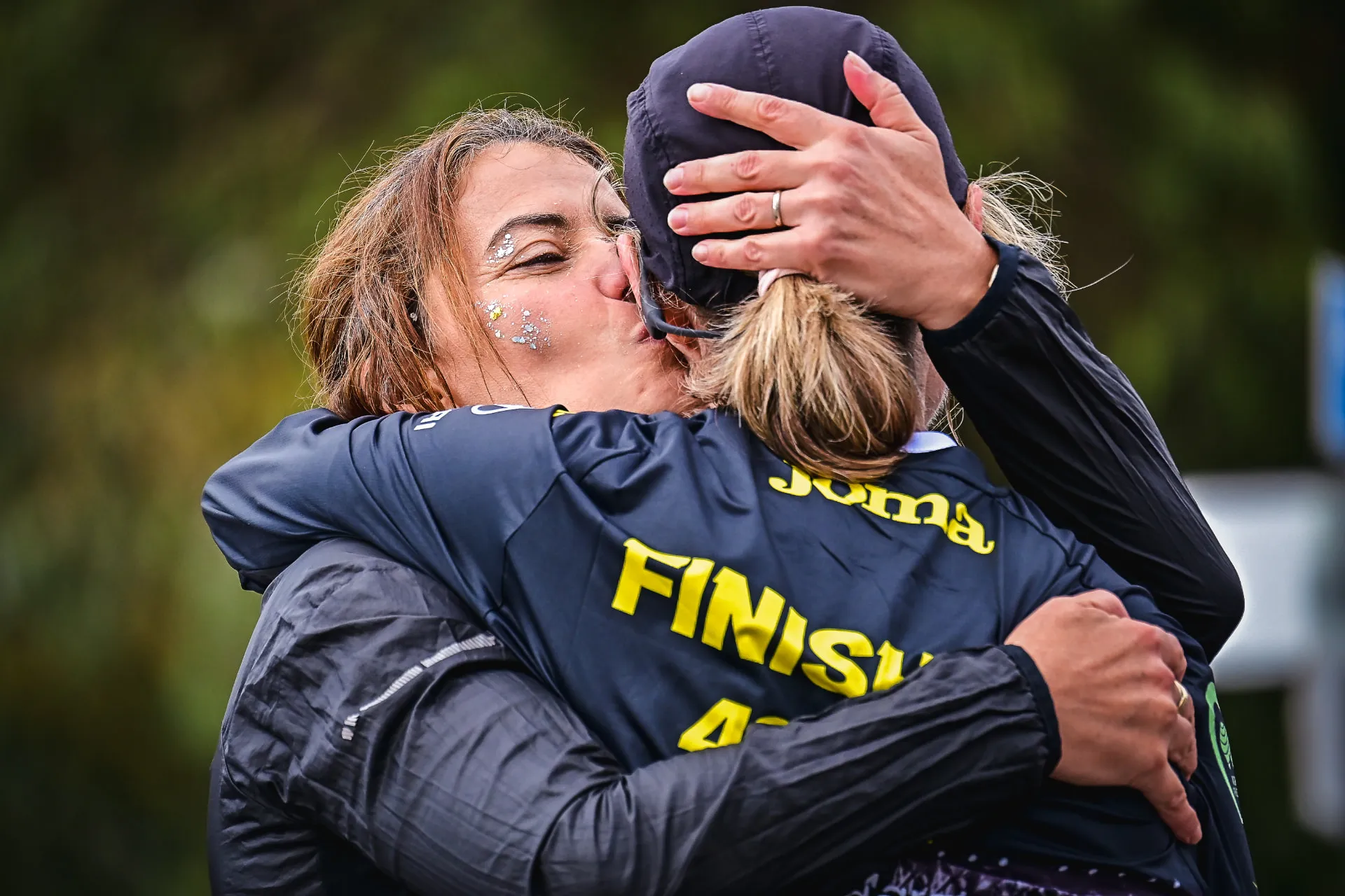 Two participants sharing an emotional embrace at the finish line of a marathon